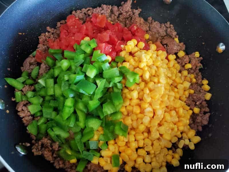 cooked ground beef with rotel, corn, and bell peppers in a large skillet