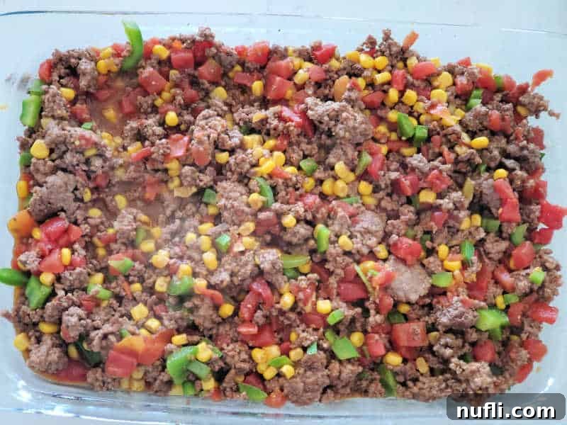 ground beef, tomatoes, corn, and bell peppers in a casserole dish
