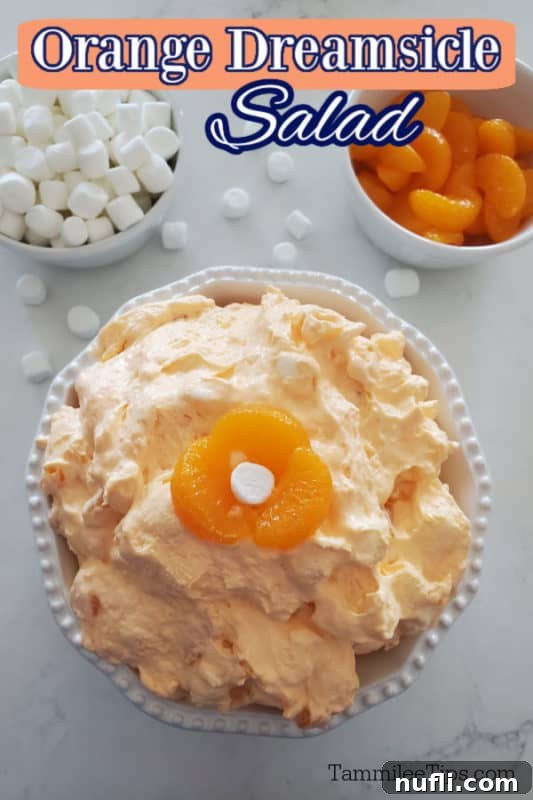 Orange Dreamsicle Salad text over a white bowl with orange jello salad in a white bowl next to a bowl of mini marshmallows and a bowl of mandarin oranges 