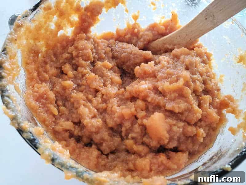 mashed sweet potatoes in a glass bowl with a wooden spoon