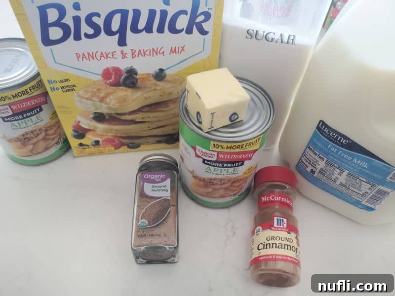 Easy Bisquick Apple Cobbler 3 Apple pie filling, Bisquick Sugar, Butter, Nutmeg, Cinnamon, and milk on a white counter.