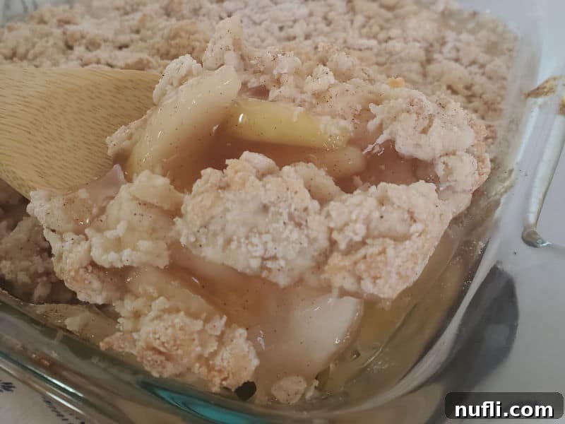 Easy Bisquick Apple Cobbler 9 Wooden spoon scooping apple cobbler out of a baking dish.