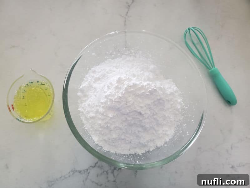 Ingredients for the Mountain Dew glaze: a mound of powdered sugar, a small bottle of Mountain Dew, and a whisk, all arranged on a clean white kitchen counter.