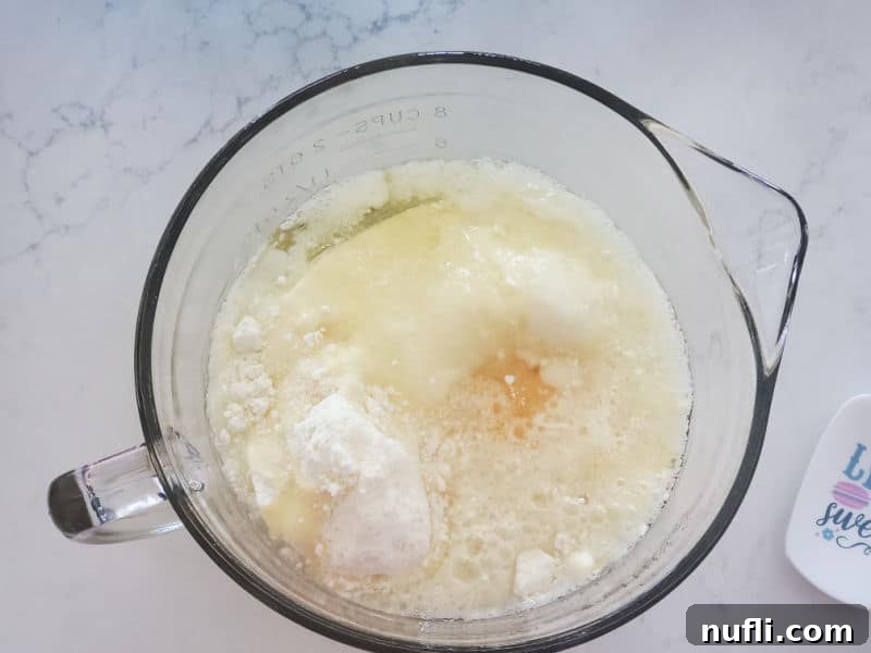 Lemon cake mix poured into a clear glass batter bowl, with a spatula resting inside, awaiting the addition of liquid ingredients.