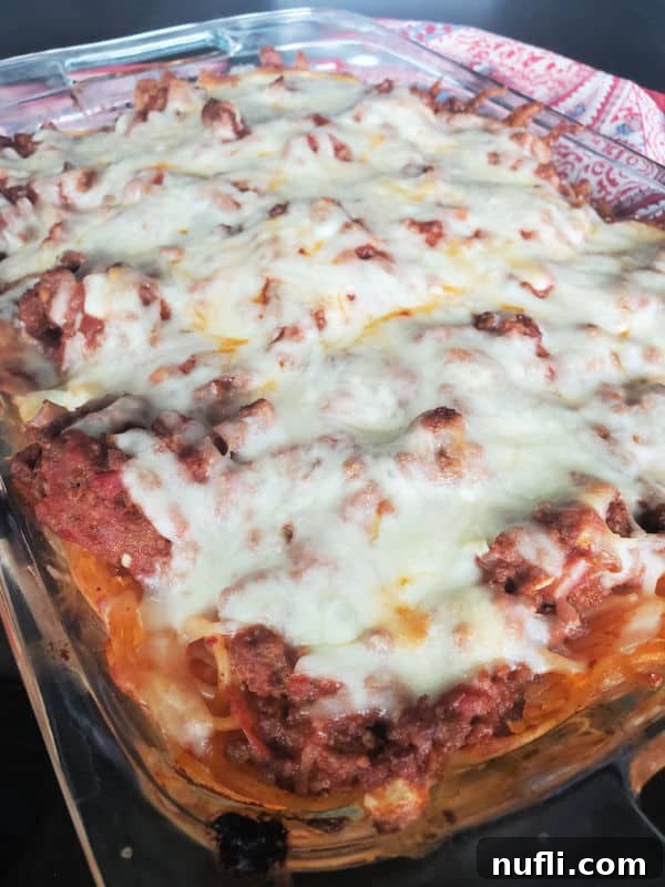 million dollar spaghetti casserole with melted cheese on top in a glass baking dish