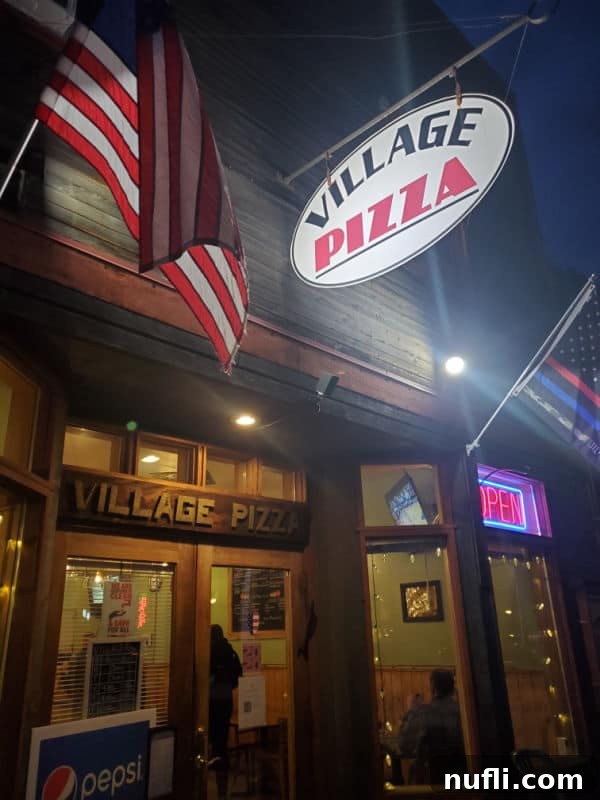 Village Pizza sign, American flag, and restaurant entrance in Roslyn. 