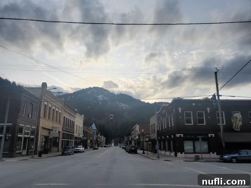 looking down the road at historic buildings, and hills with trees and snow on them 