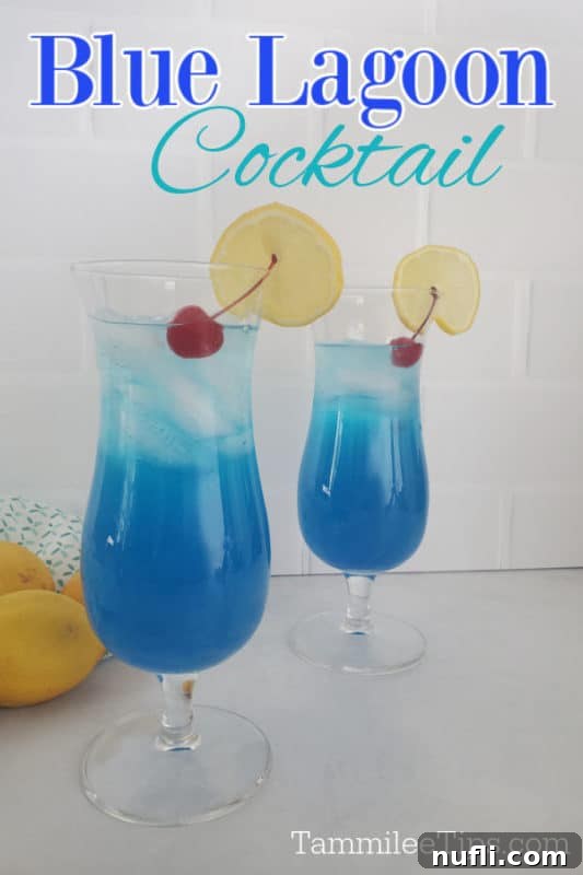 Two hurricane glasses filled with a vibrant blue Blue Lagoon Cocktail, garnished with a maraschino cherry and a lemon wheel.