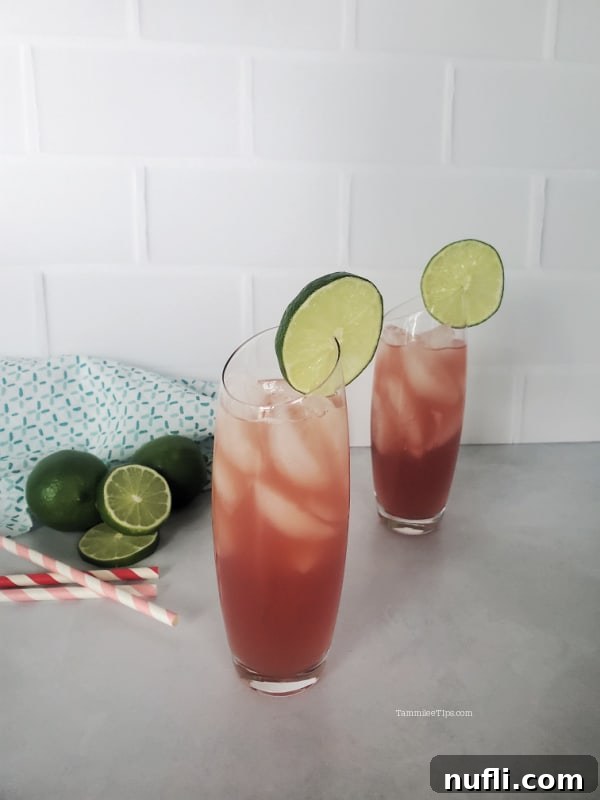 Two finished Bay Breeze cocktails on a white counter, garnished with lime wheels and served with paper straws.
