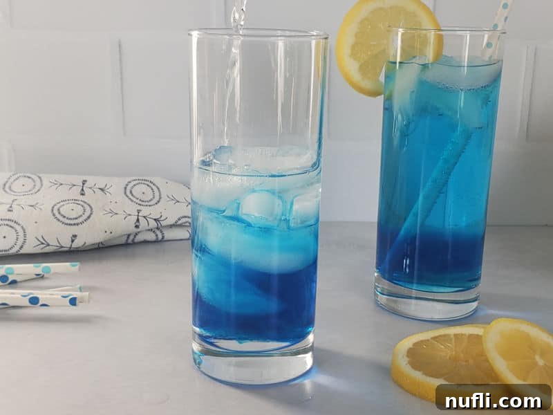 Shake Up the Sex in the Driveway: Video Cocktail Recipe 6 Vodka being poured into a tall glass containing ice and blue liquid, next to a finished blue cocktail with a lemon wheel.