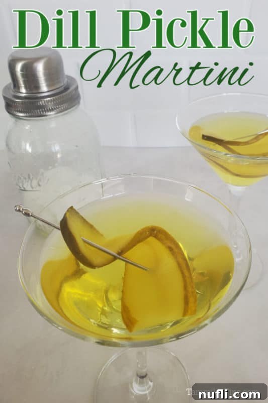 Pickle martini over two martini glasses with cocktails and pickle garnishes sitting next to a cocktail shaker