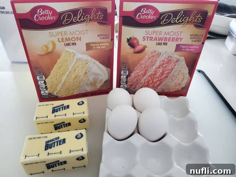 Essential ingredients for Strawberry Lemonade Cookies: lemon cake mix, strawberry cake mix, softened butter, and fresh eggs laid out on a clean white counter.