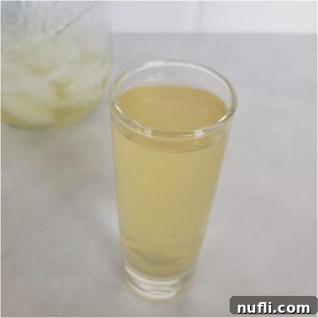 Green tea shot in a clear shot glass next to a mason jar
