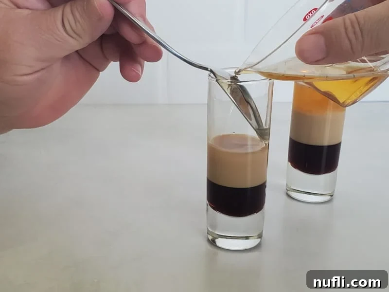 Crafting the B52 Shot A Video Guide 7 Grand Marnier Orange Liqueur being carefully poured into a shot glass, completing the B52 cocktail.