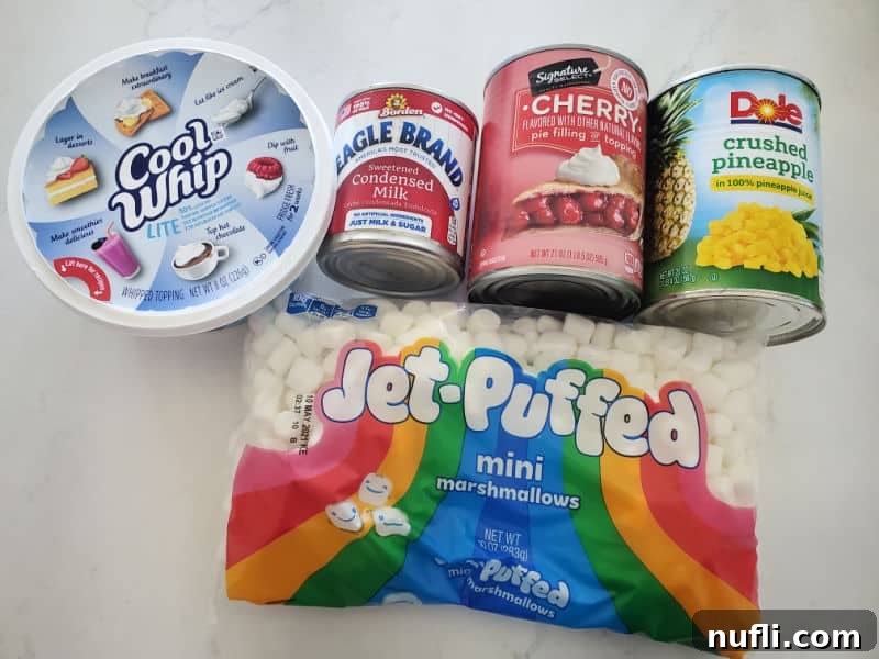 Cool whip, condensed milk, cherry pie filling, crushed pineapples, and a bag of mini marshmallows on a white counter