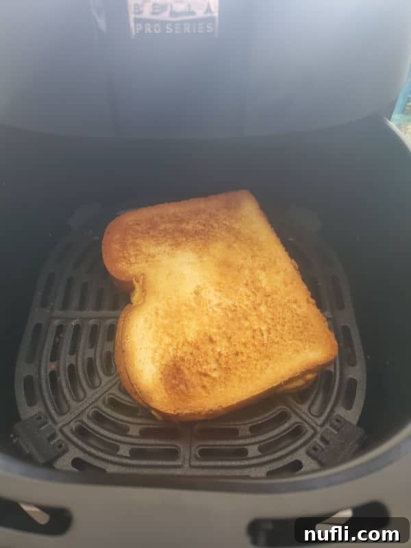 Air fried grilled cheese cooking in the air fryer basket, showing a golden brown crust