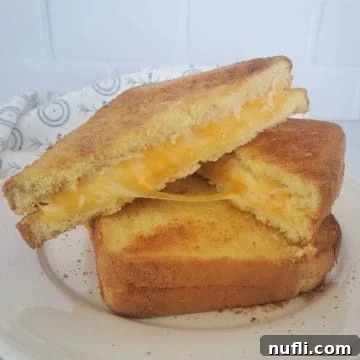 Two air fried grilled cheese sandwiches stacked on a white plate