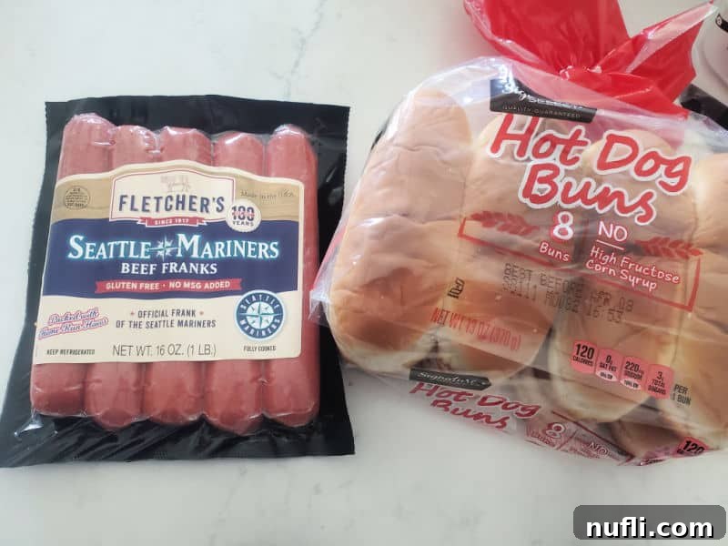 A package of Fletchers Seattle Mariners hot dogs displayed next to a fresh pack of hot dog buns, hinting at the simple ingredients for a delicious meal.