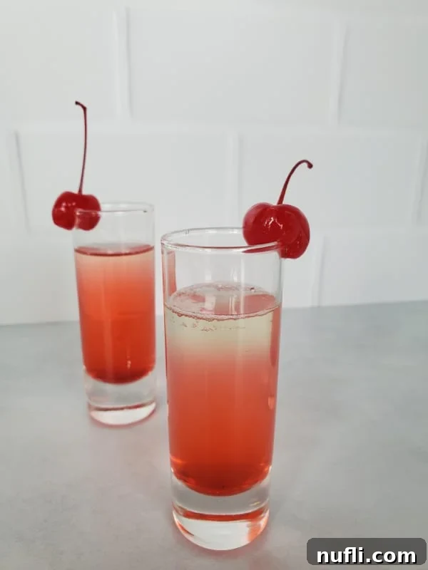 2 Pineapple upside down cake shots with maraschino cherries on the glass