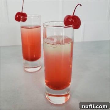 layered red cocktail garnished with cherries