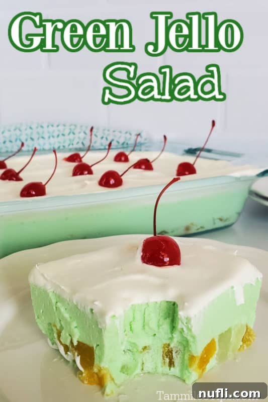 Green jello salad over a square on a plate next to the platter of jello salad