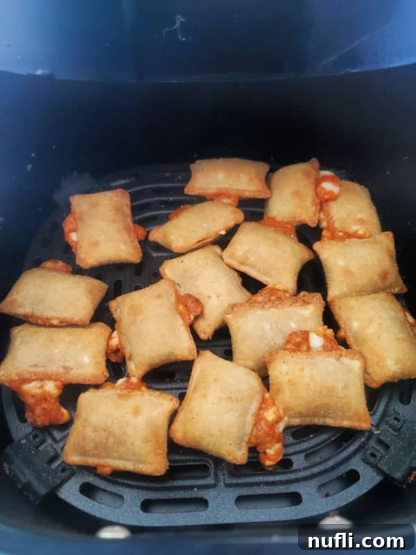 Perfectly air fried pizza rolls displayed in a black air fryer basket, steam rising.
