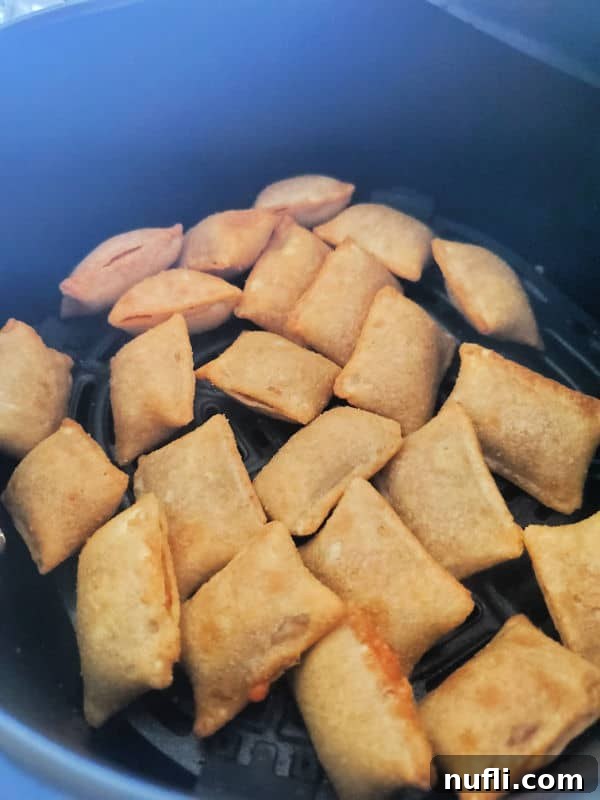 Close-up of crispy, golden-brown air fryer pizza rolls in the air fryer basket.
