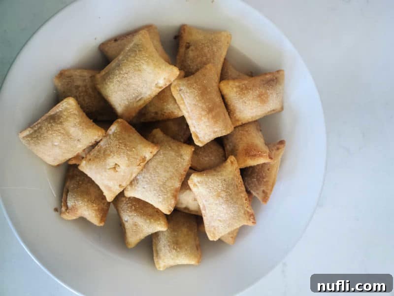 Air fryer pizza rolls served in a white bowl on a white counter, ready for dipping.