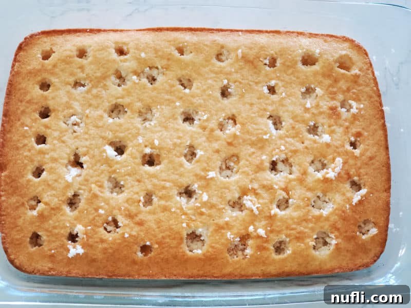 White cake with holes poked in the top of it in a baking dish
