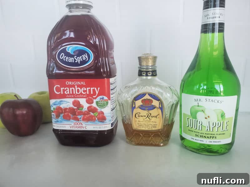 Red and green apples next to a bottle of cranberry juice, Crown Royal, and sour apple schnapps