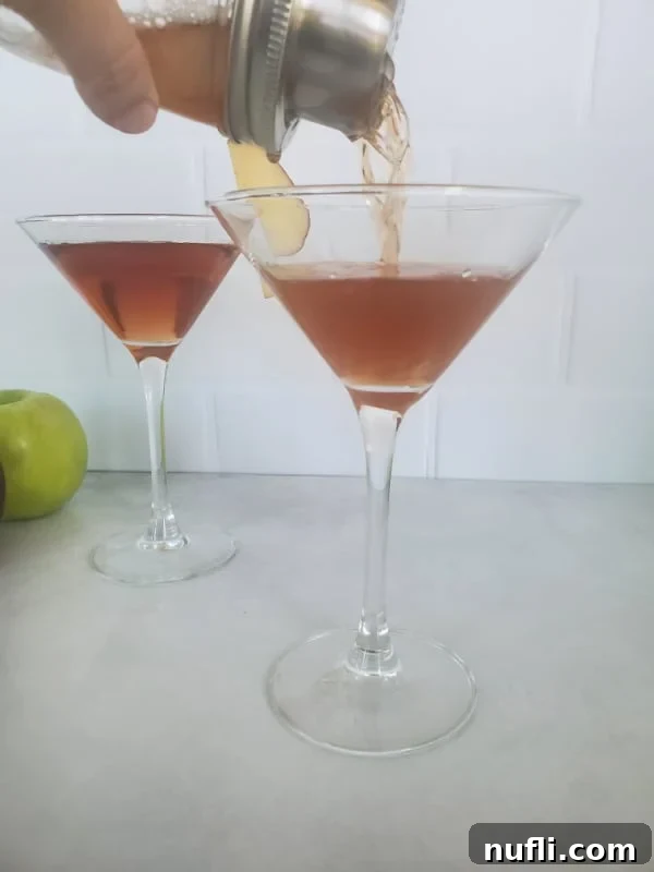 Cocktail shaker pouring a Washington apple drink into a martini glass