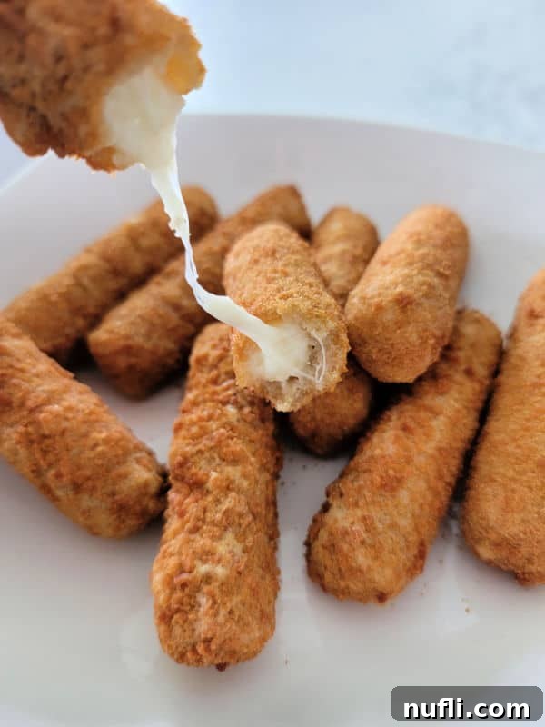 cheese pull from an air fried mozzarella stick on a white plate