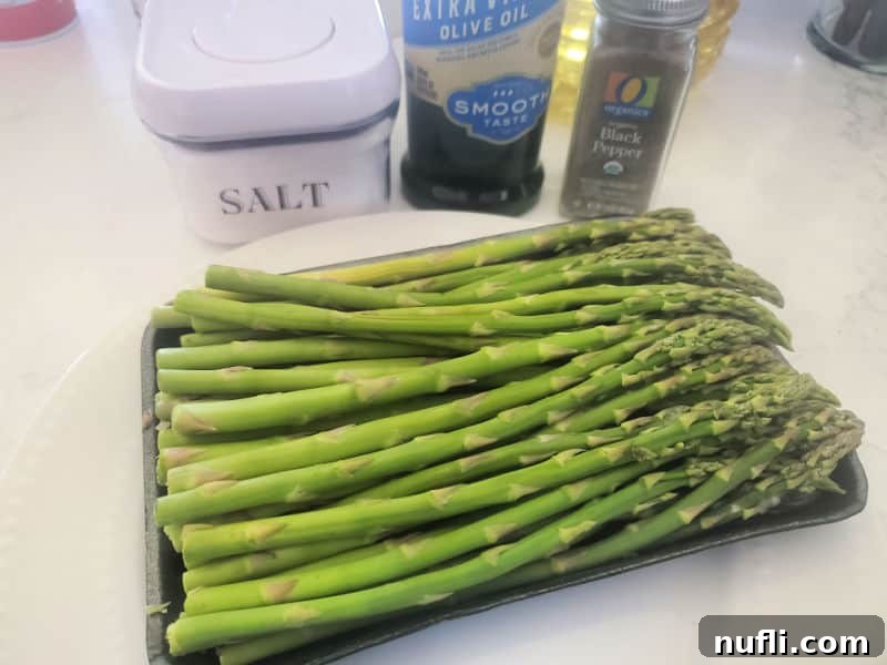 Air-Fried Asparagus 3 Salt, olive oil, pepper, and fresh asparagus laid out on a white counter, ready for preparation