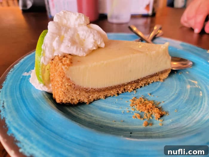 Slice of tangy key lime pie with whipped cream garnish on a turquoise plate