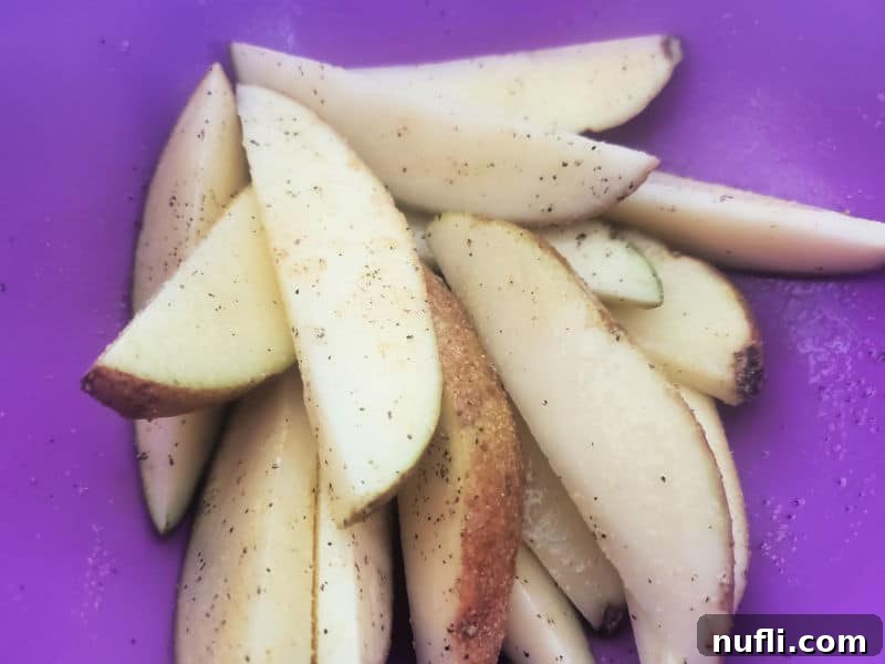 Seasoned potato wedges coated in a vibrant purple bowl, ready to be air fried.