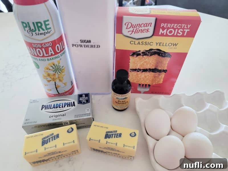 Ingredients for Ooey Gooey Butter Cake: powdered sugar, yellow cake mix, cream cheese, butter, and eggs, laid out on a clean surface.