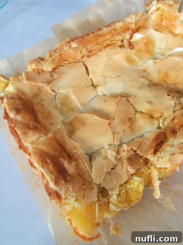 Freshly baked Ooey Gooey Butter Cake bars on parchment paper, ready to be served.