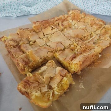 Ooey Gooey Butter Cake recipe on parchment paper with a cloth napkin, ready to be served.