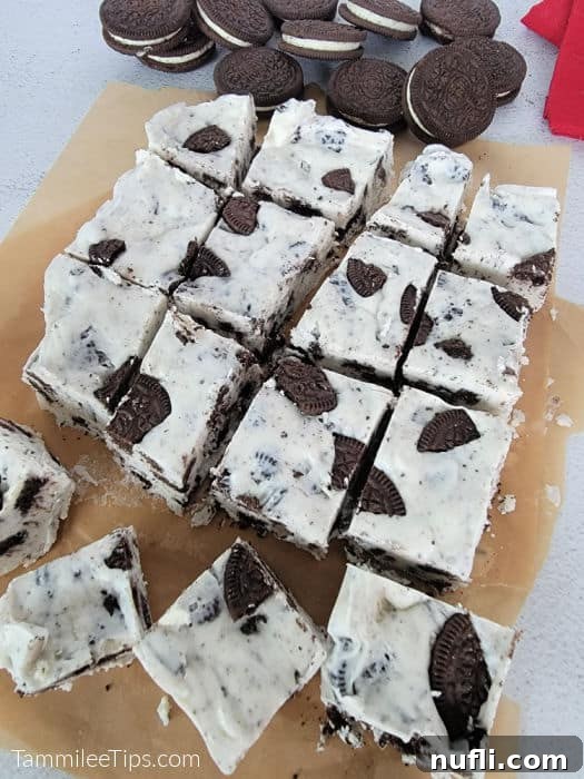 Easy 3-Ingredient Oreo Fudge 5 Freshly made Oreo fudge, cut into neat squares and resting on parchment paper, with a scattering of whole Oreo cookies in the background, ready to be enjoyed.
