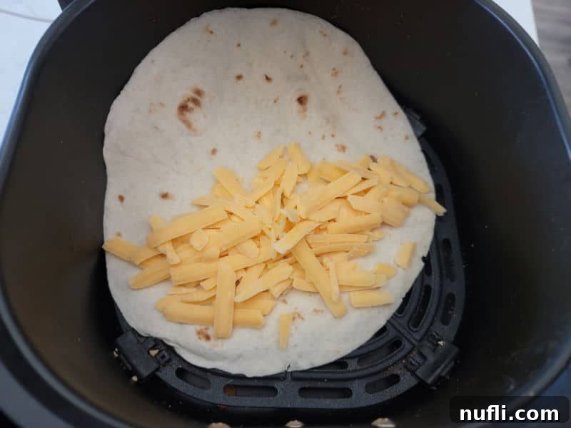 Crispy Air Fryer Quesadillas 4 shredded cheese on a tortilla in the air fryer basket