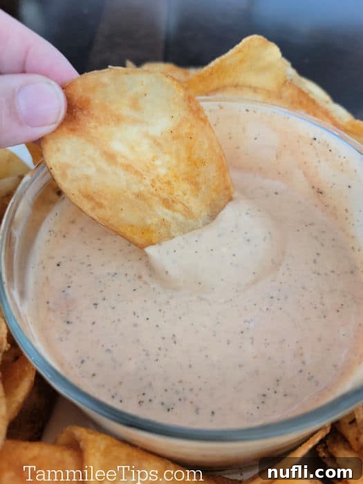 Potato chip dipping into Zax's Sauce in a glass bowl