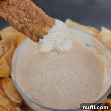 Chicken tender dipping into Zaxby's Sauce in a glass bowl