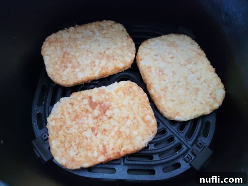 Frozen hashbrown patties in an air fryer basket