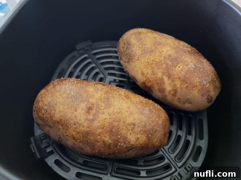 two potatoes in an air fryer basket