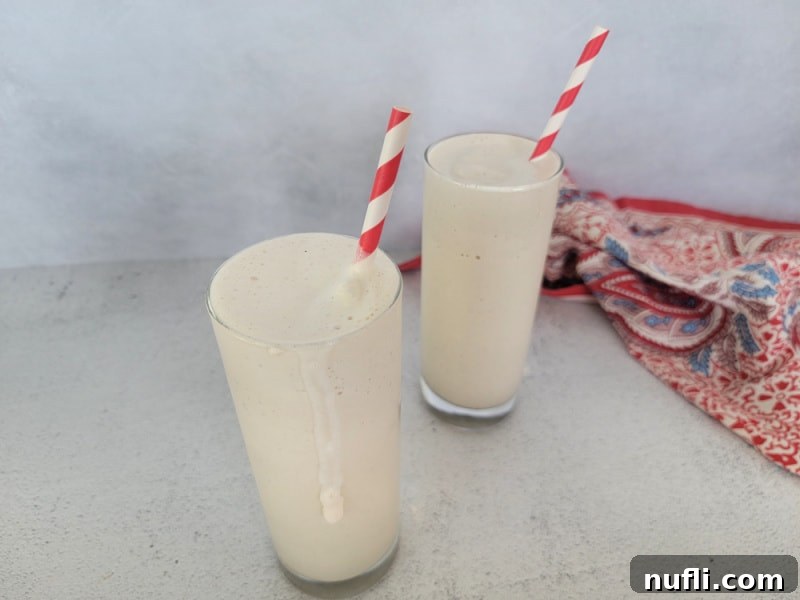 Two tall glasses with Chick fil a frosted coffee in them, red and white striped paper straws red and blue napkin to the side of them. 