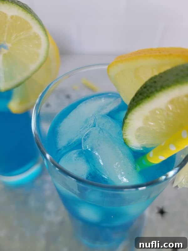 Close up of an electric lemonade blue cocktail with lemon and lime garnish