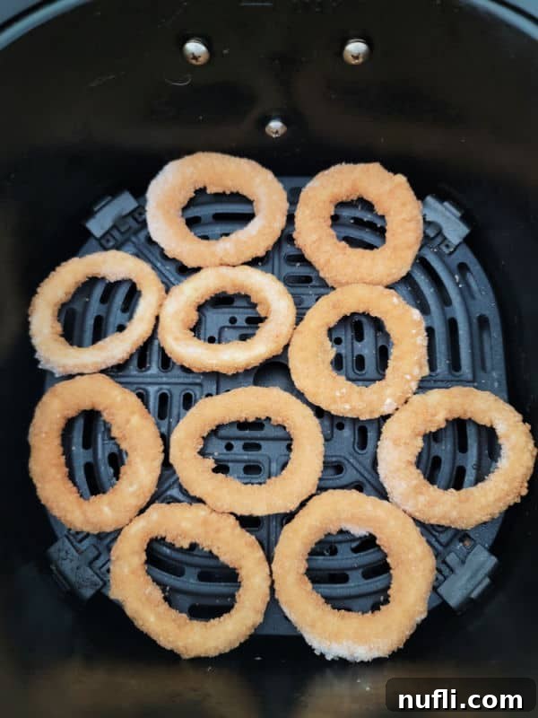 frozen onion rings spread in an air fryer basket