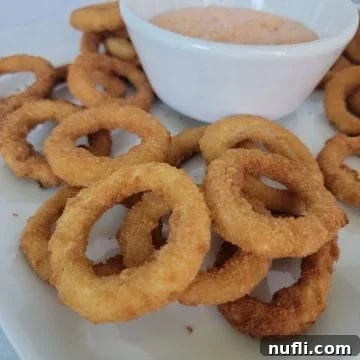 a plate with onion rings and dipping sauce in a bowl