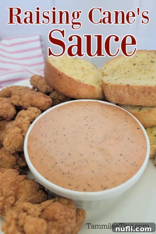 Raising Cane's Sauce over a bowl filled with sauce, garlic bread, and chicken pieces 