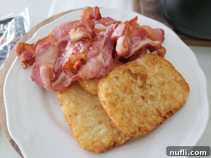 Air fryer basket on a white plate with hashbrowns. 